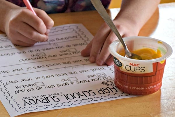 kid writing on the survey eating macaroni and cheese