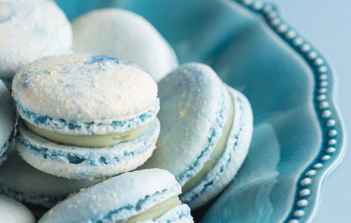 Close-up of blue cotton candy macarons in a blue bowl.