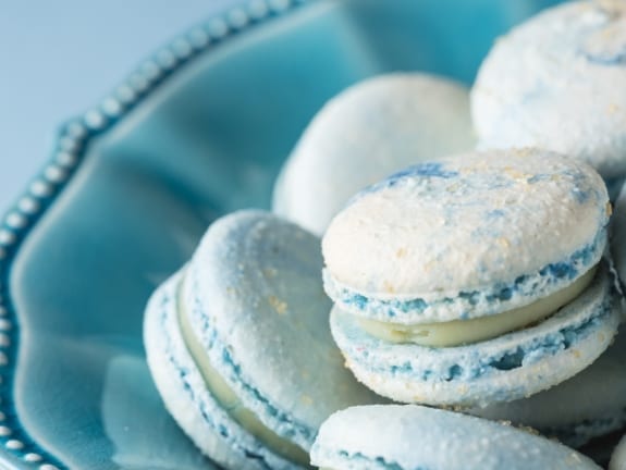 Closeup of cotton candy french macarons in a blue bowl.