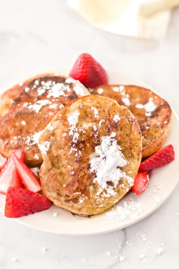 a plate with english muffin french toast on it with strawberries