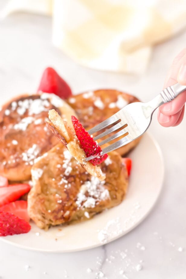 fork with a slice of french toast and strawberry on it