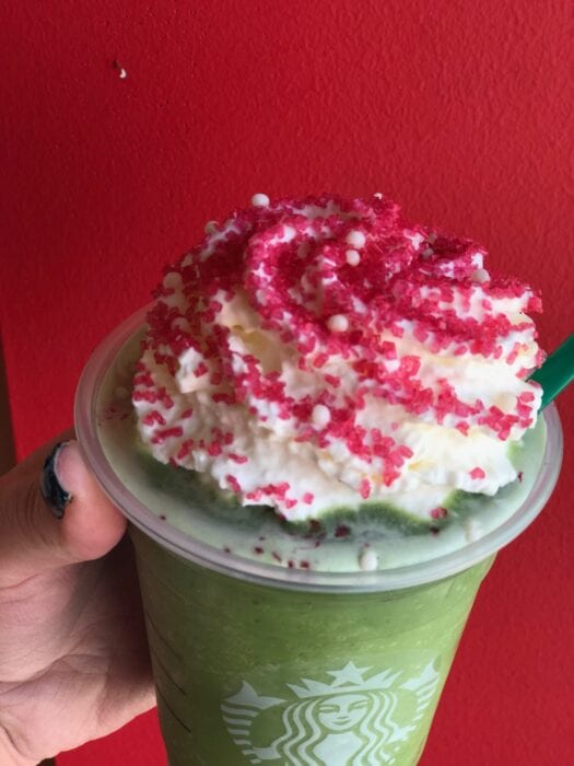 this Buddy The Elf Frappuccino is topped with whipped cream and red sugar for a festive look