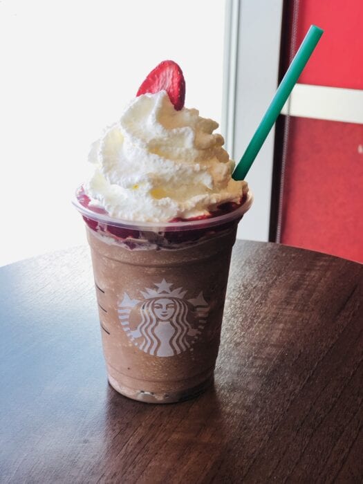 a mocha frappuccino topped with strawberry puree and a fresh strawberry slice resembles a cute Rudolph The Reindeer