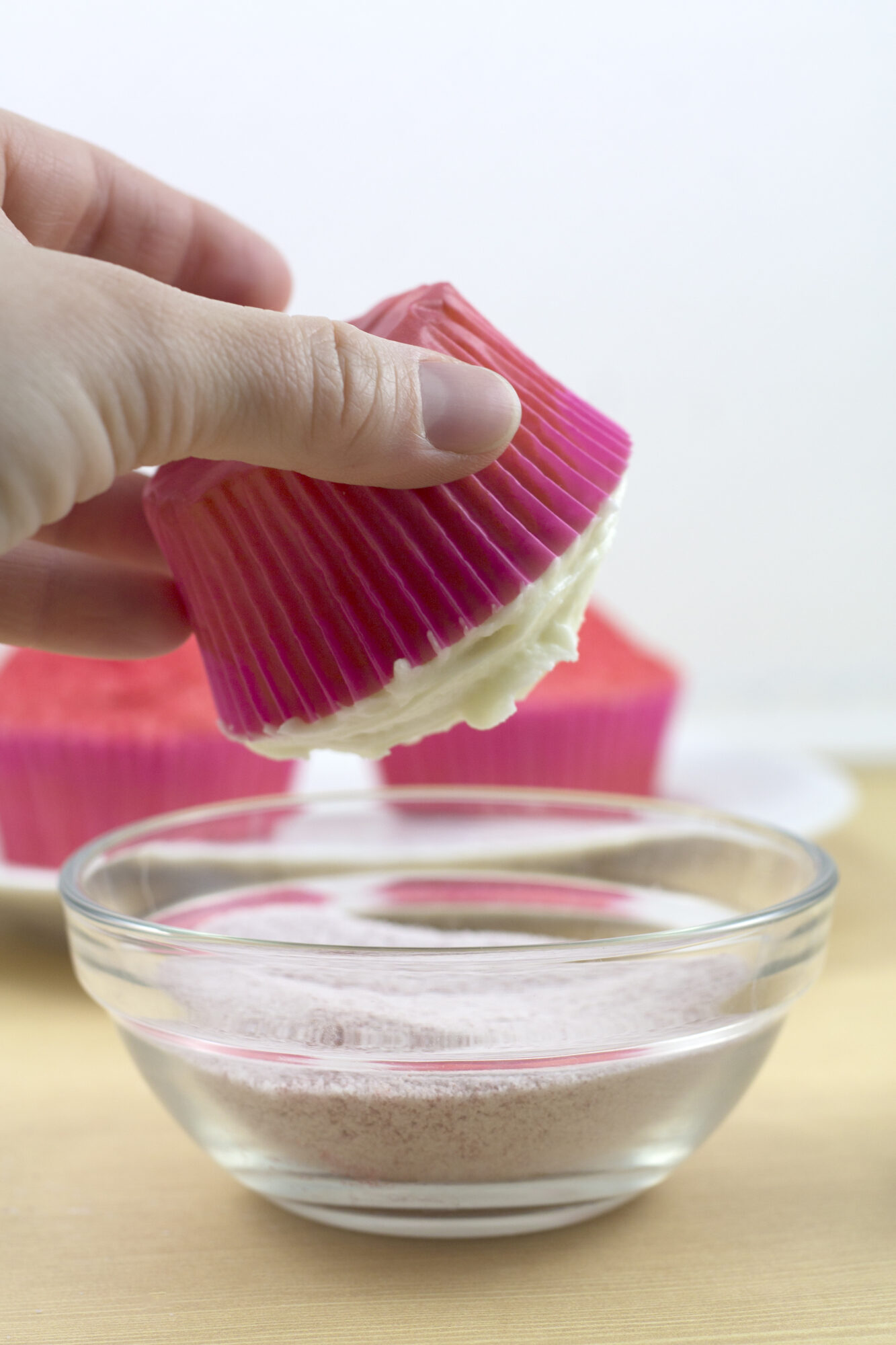 hand dipping cupcake into topping sprinkles