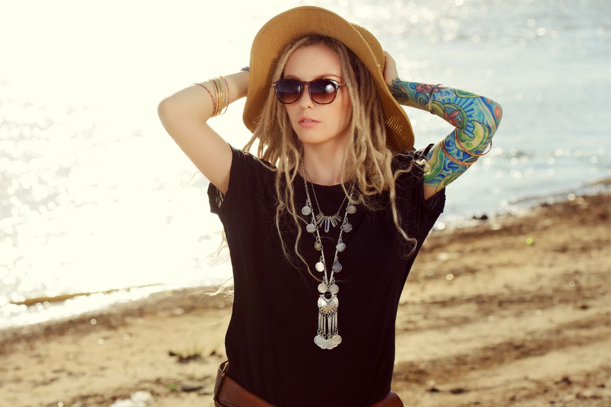 woman dressed like a hippie with lots of jewlery, hat and shorts