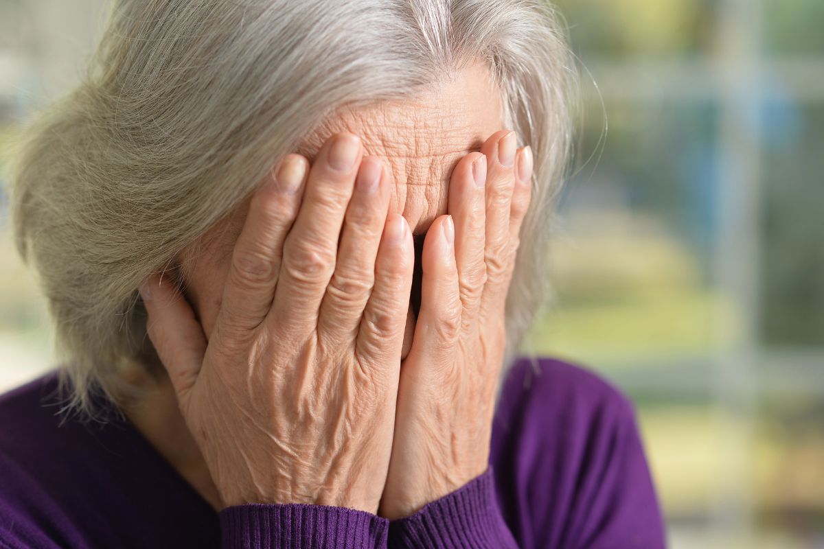 Older woman covering her face worried