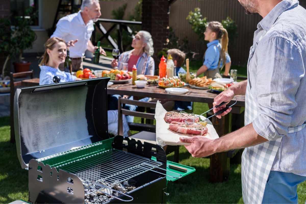 family at a bbq, man holding steaks
