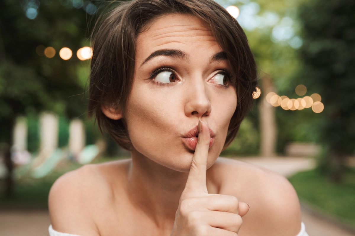 woman holding her fingers to her lips in secret