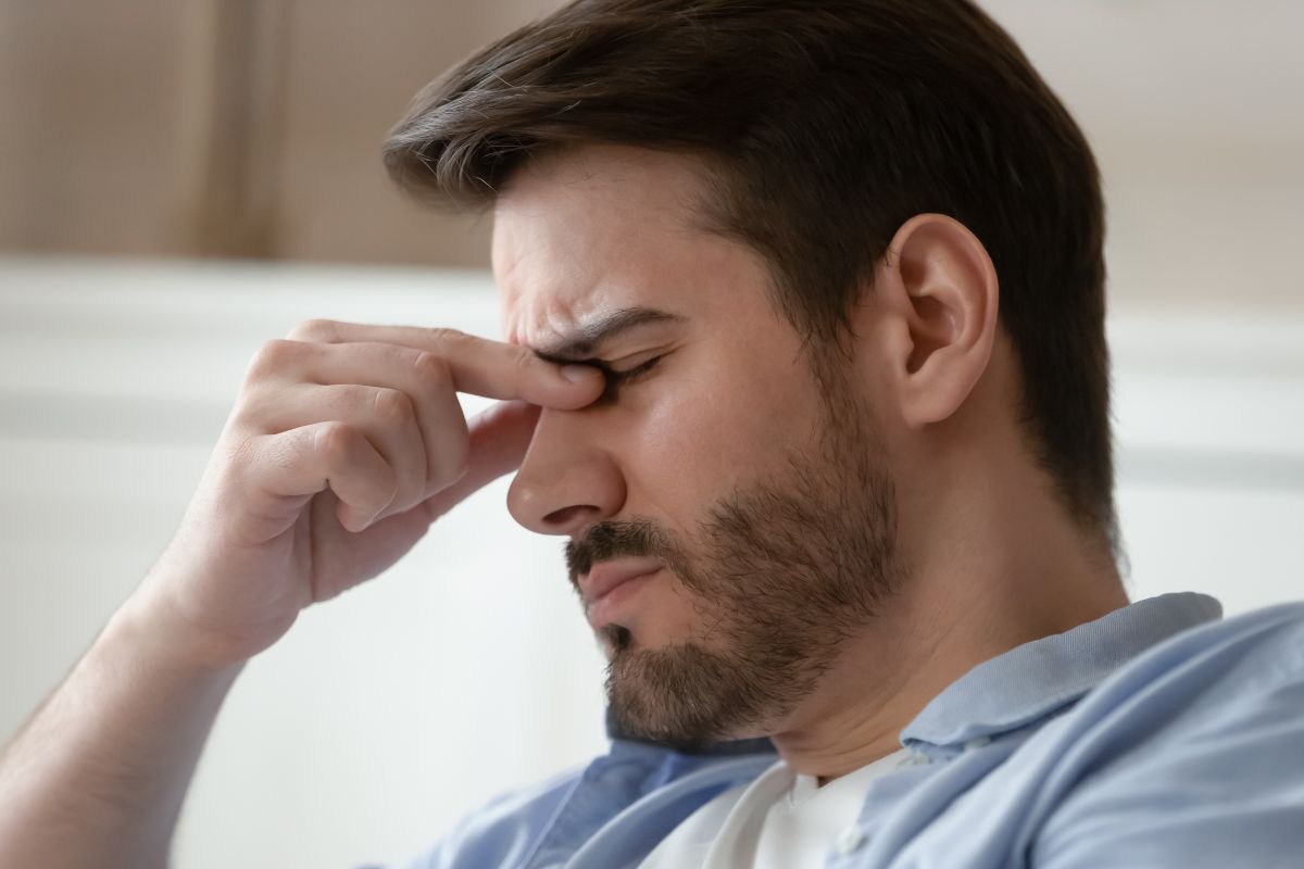 man frustrated holding his nose