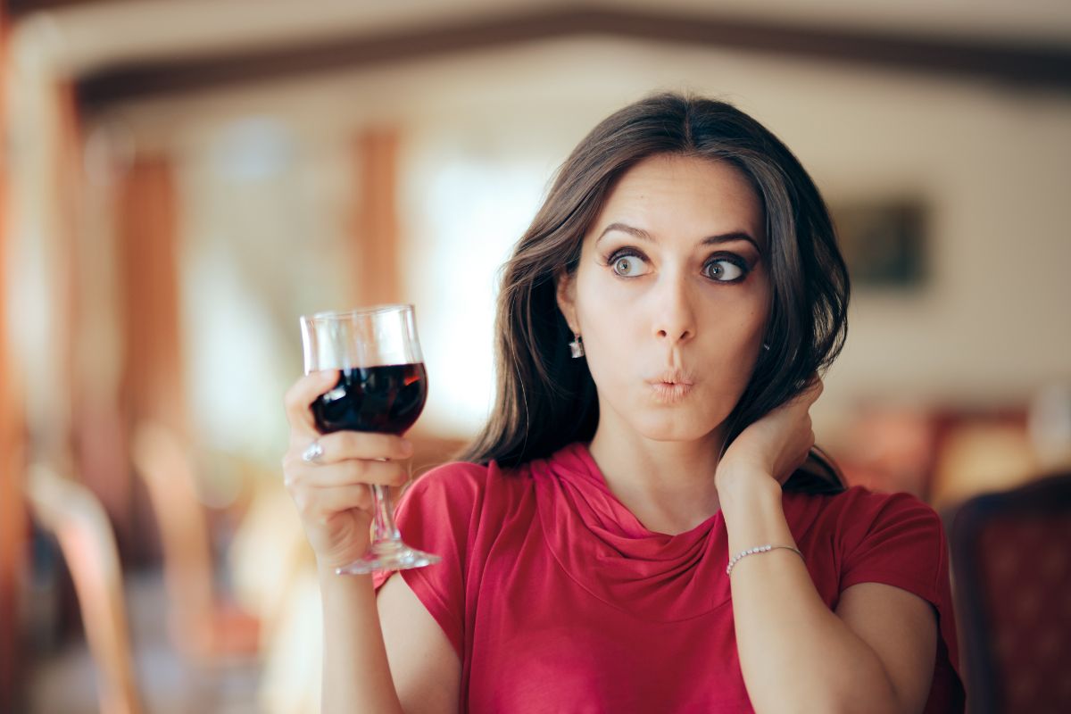 woman holding a wine glass looking shocked