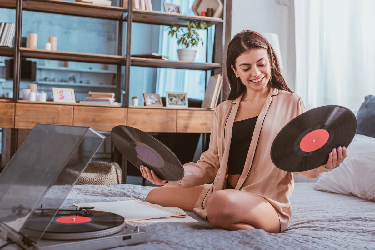 woman on her bed listening to records