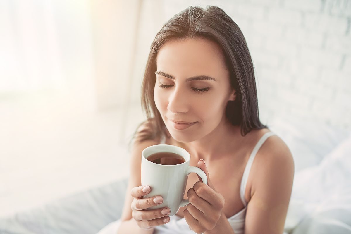 Woman in bed smelling coffee