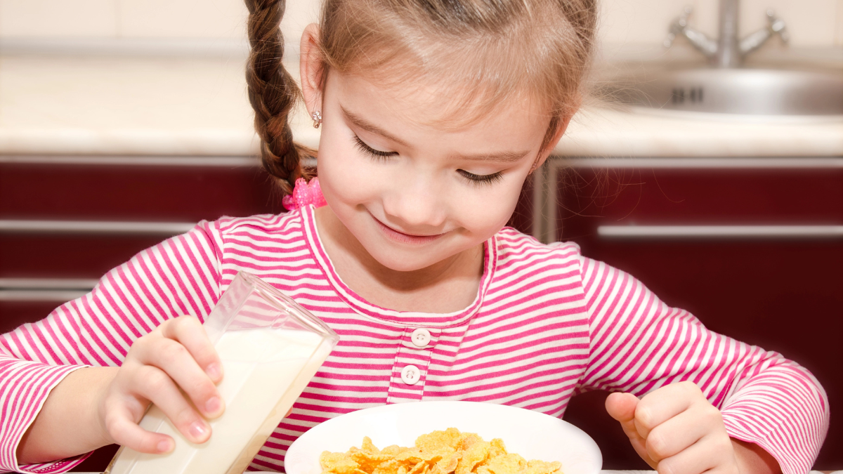 girl pouring milk on cereal