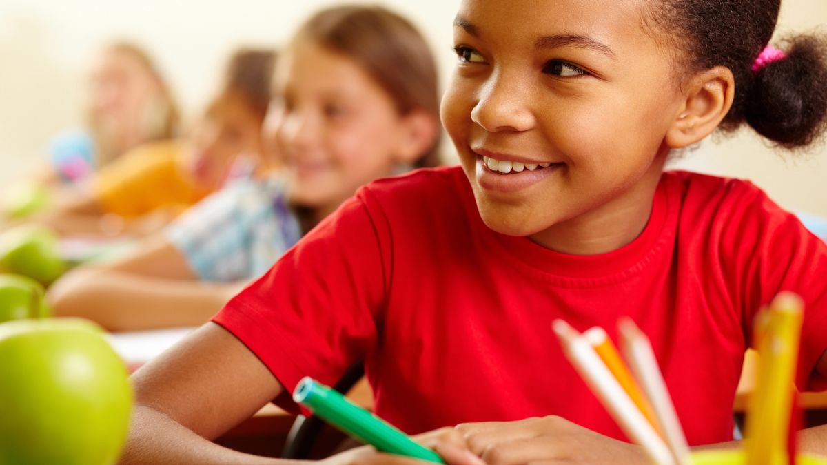 little girl smiling at desk working with marker