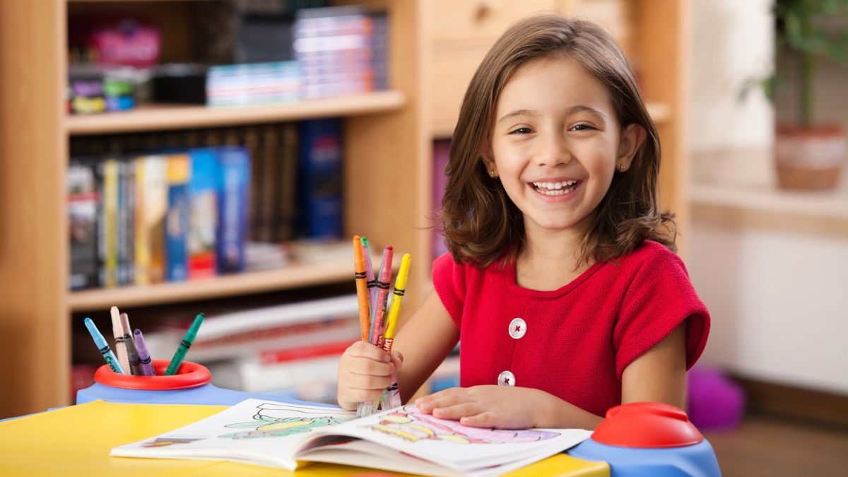 little girl smiling in school with crayons