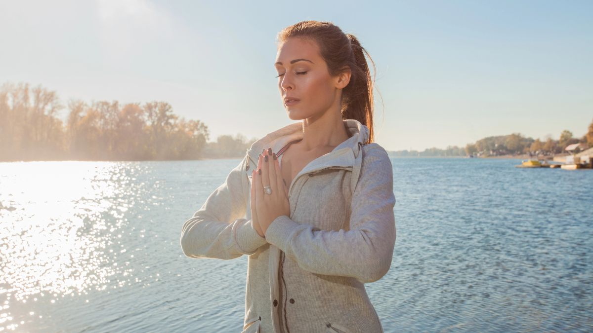 woman meditating by water outside