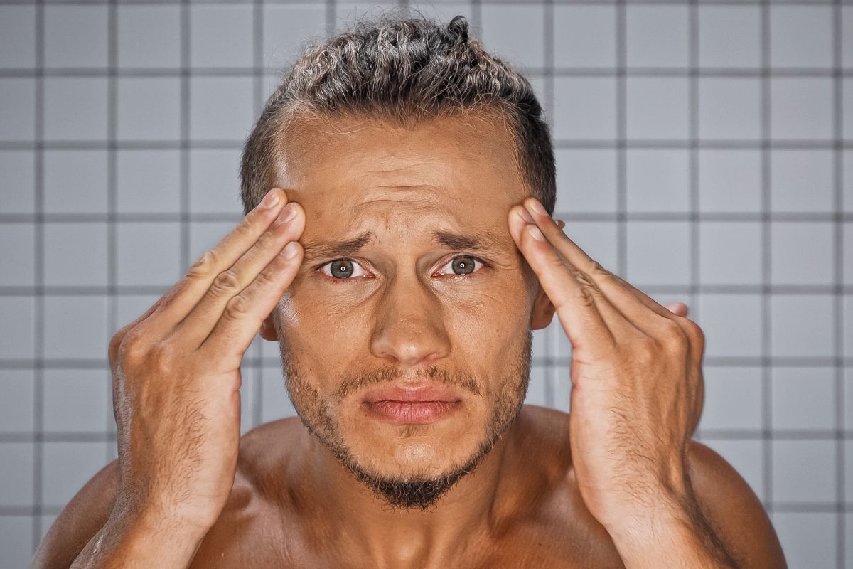 Man holding his face looking into a mirror