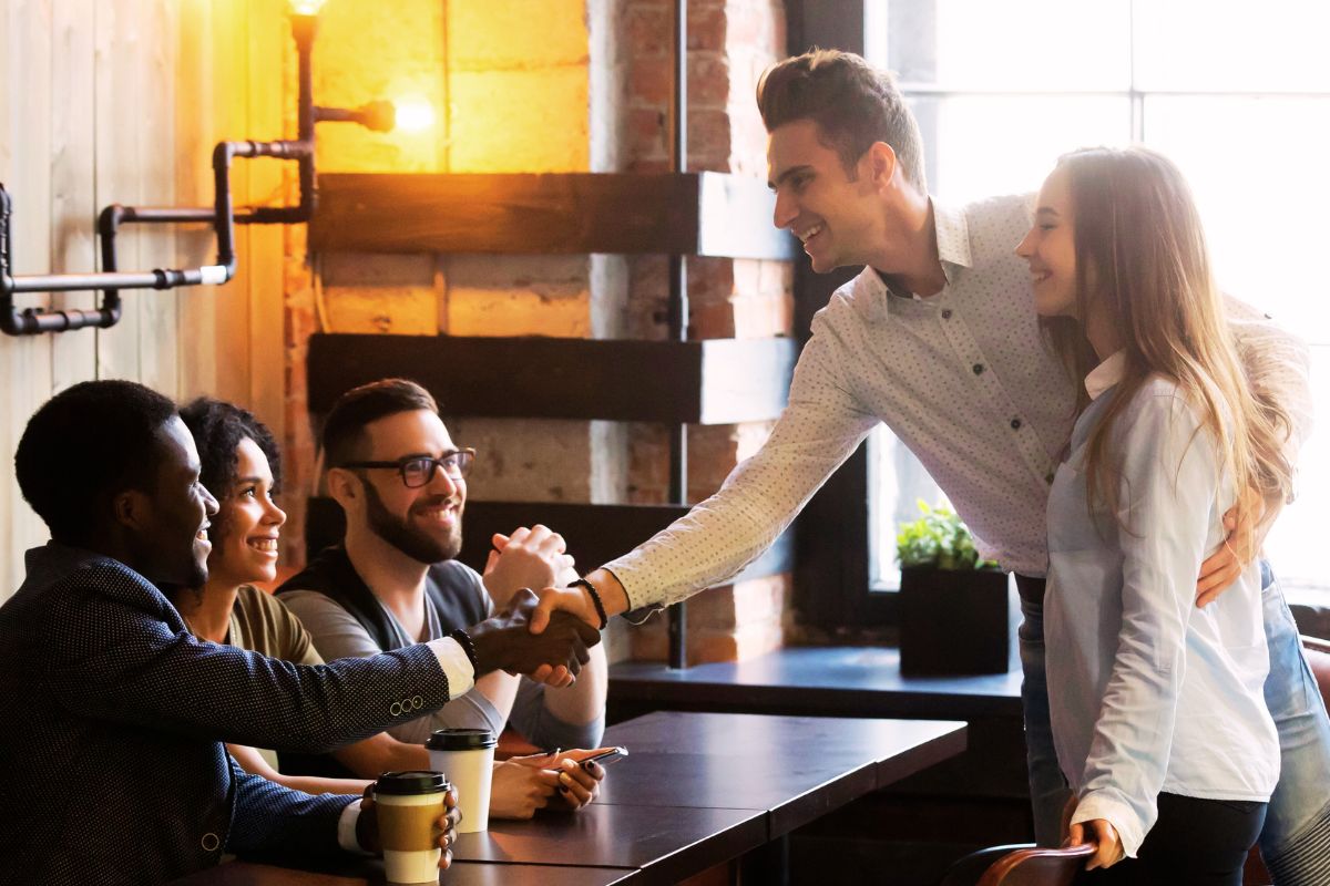 Man shaking hands while politely also holding his girlfriend