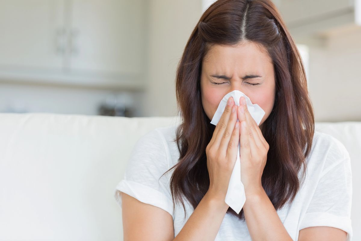 Woman sneezing into a tissue.