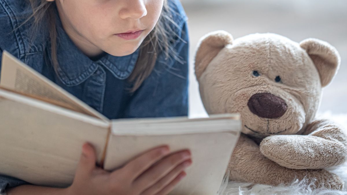 child reading with stuffed bear