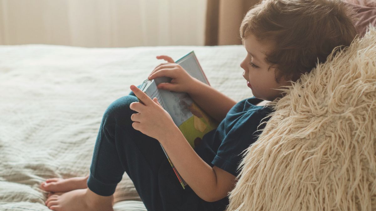 little boy reading on bed