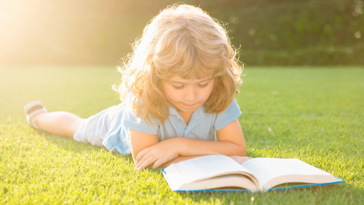 little girl reading on the grass