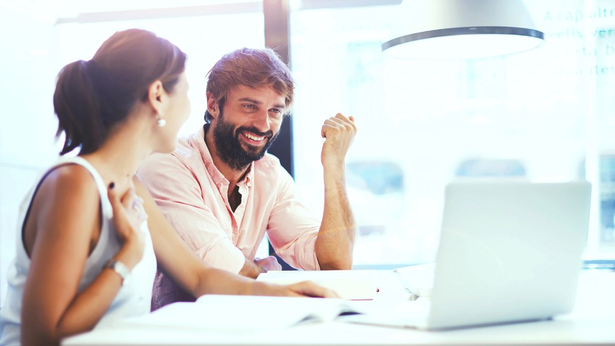 man woman talking at computer smiling