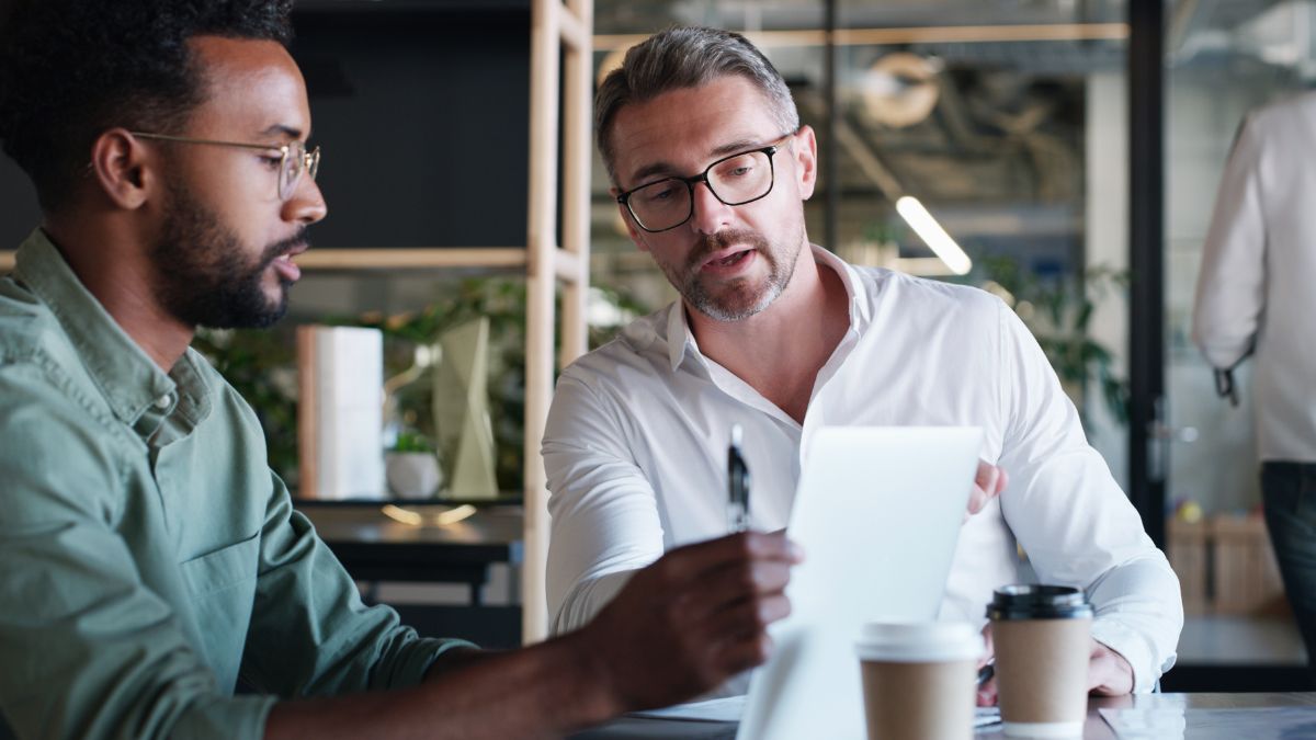 men looking at paper talking at work