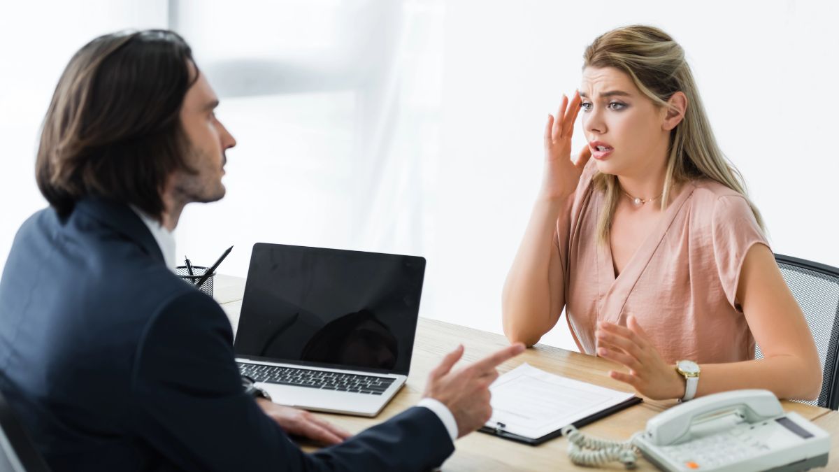 stressed woman talking to man at desk