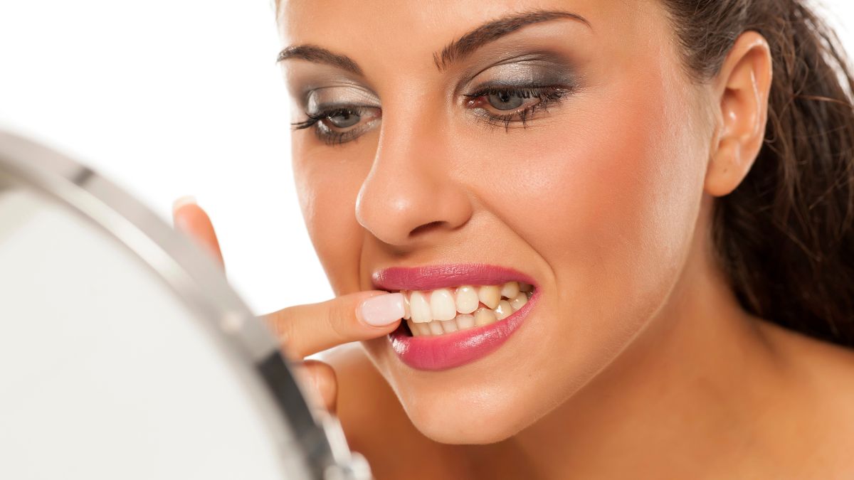 woman picking teeth in mirror