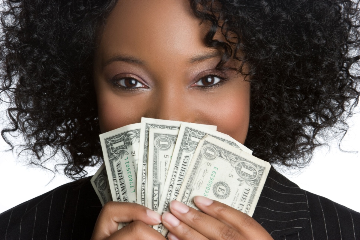 Black woman hiding behind fan of money dollars