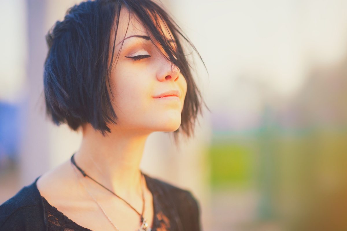 Beautiful young woman relaxing and enjoying sun at sunset.