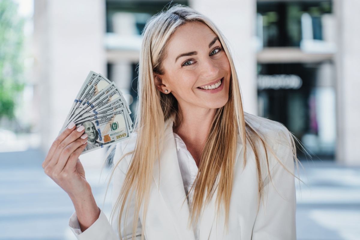 blonde woman smiling with money fan