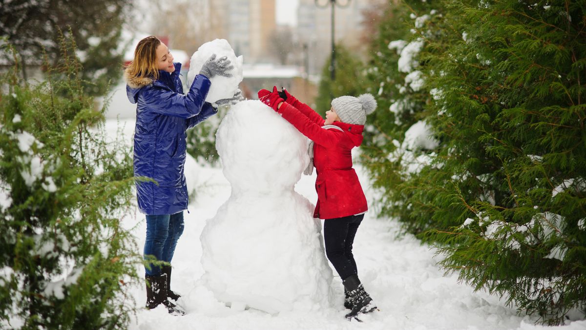 mom and daughter building a snowman