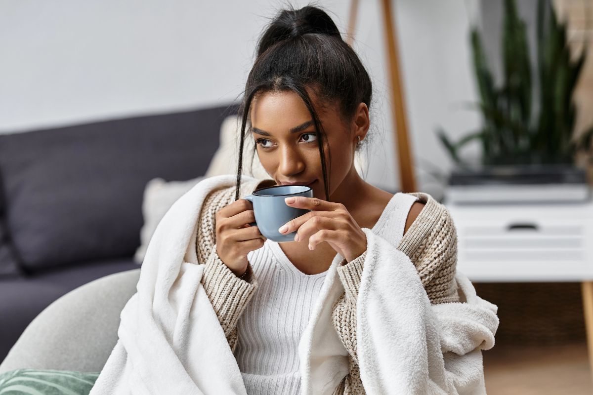 woman sipping coffee in the morning wrapped in a blanket