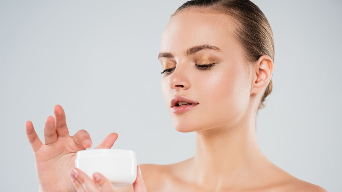 woman dipping finger in face cream