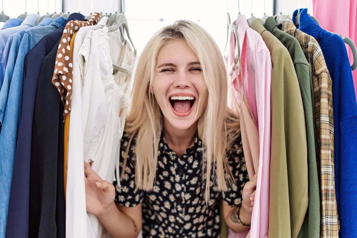 woman in between a clothing rack smiling