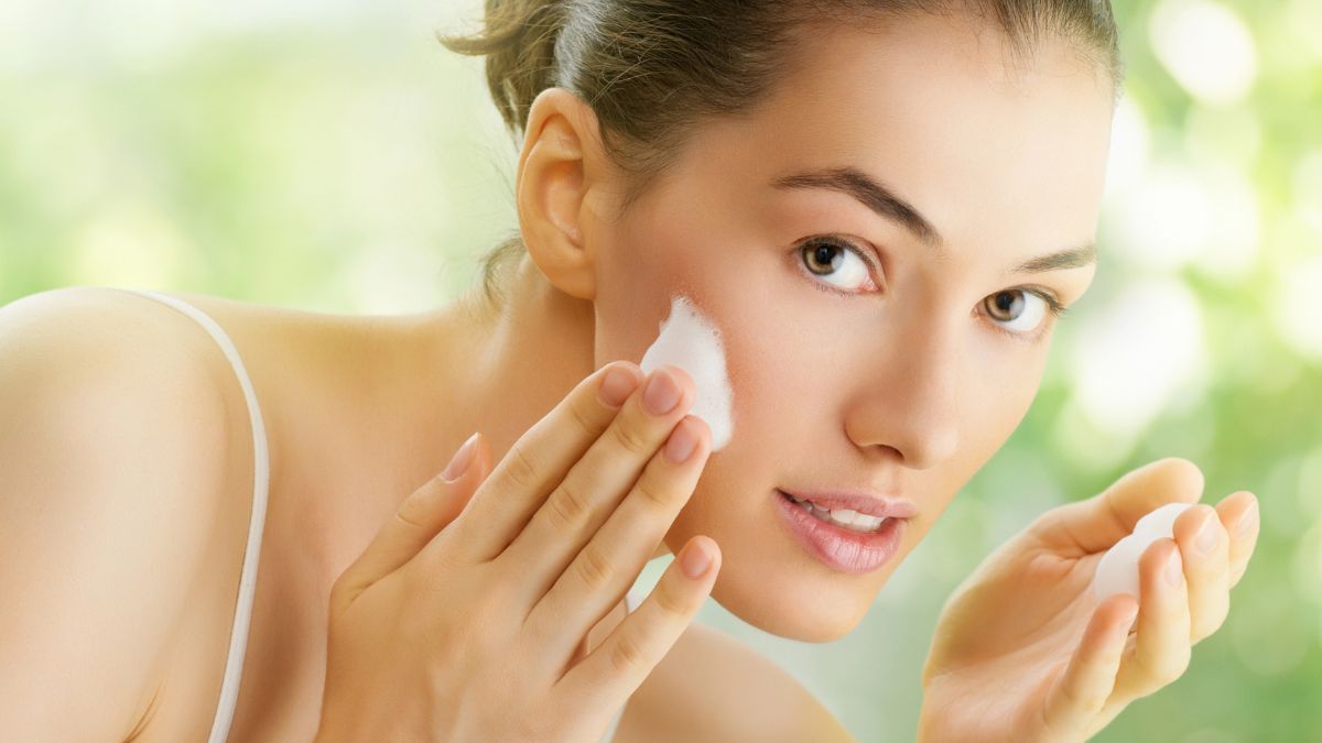 woman putting face cream on with hands