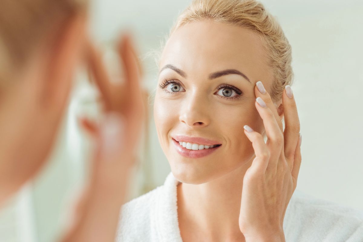 woman putting on cream in the mirror