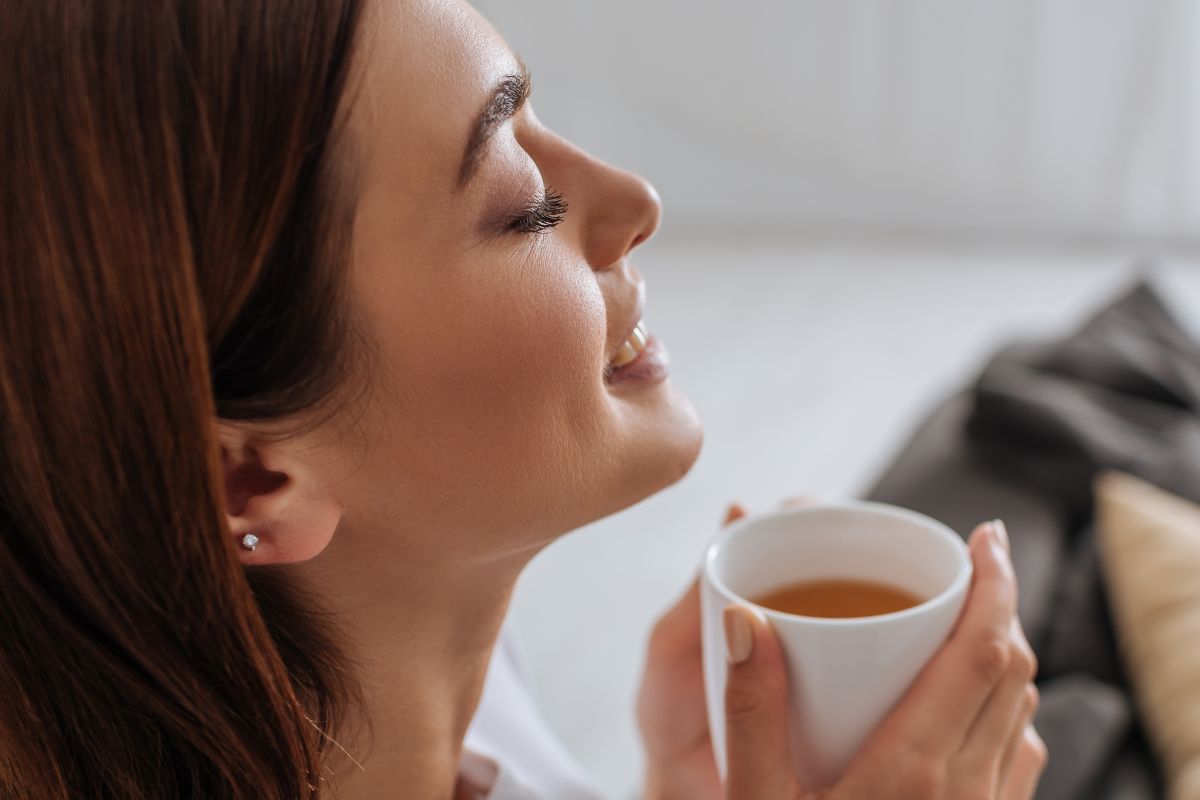 woman smiling while sipping tea