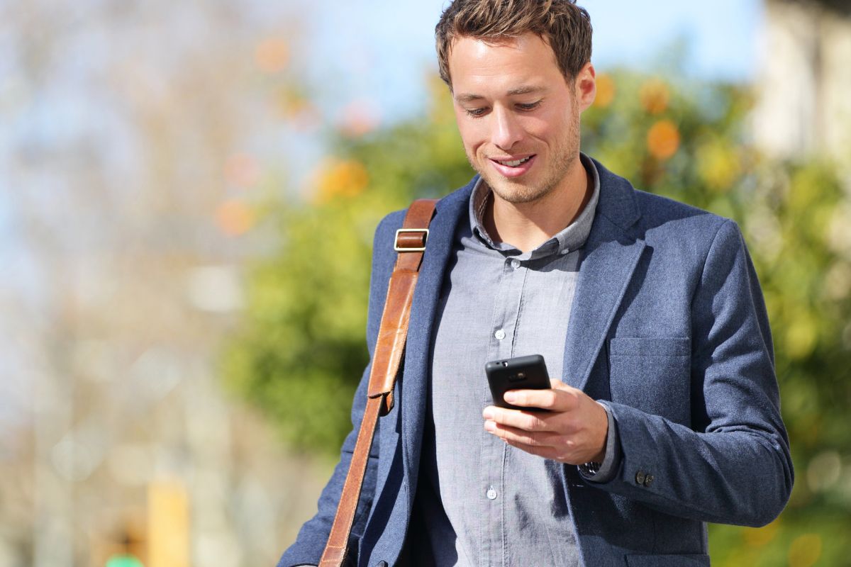 business man walking while looking at his phone