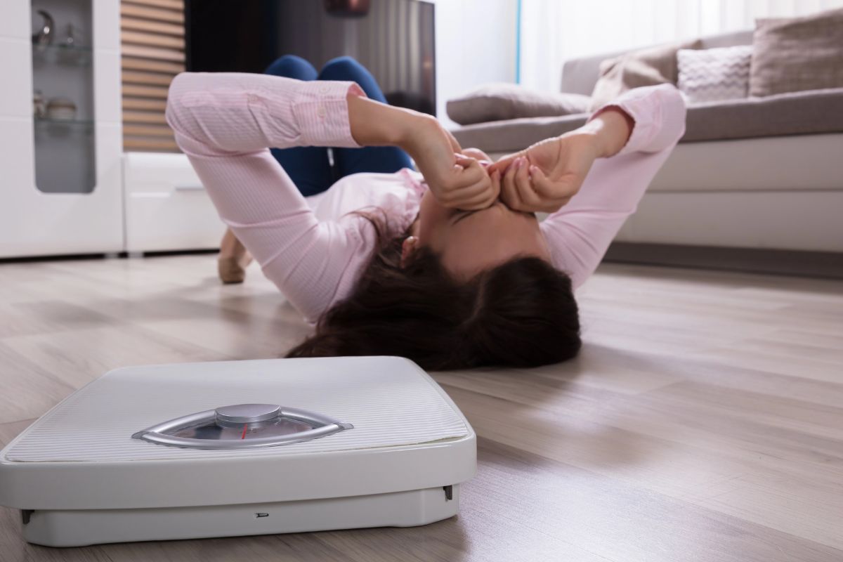 woman laying on the floor with a scale next to her