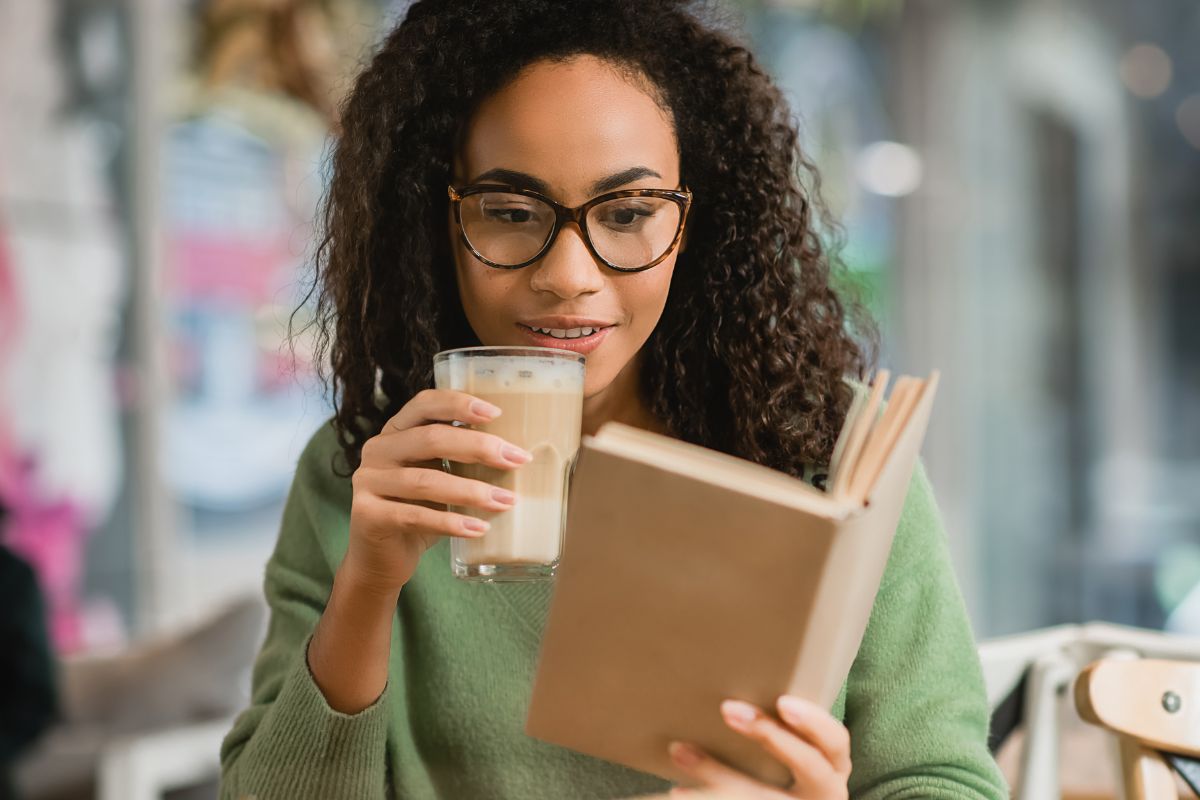 woman reading while drinking an iced coffee