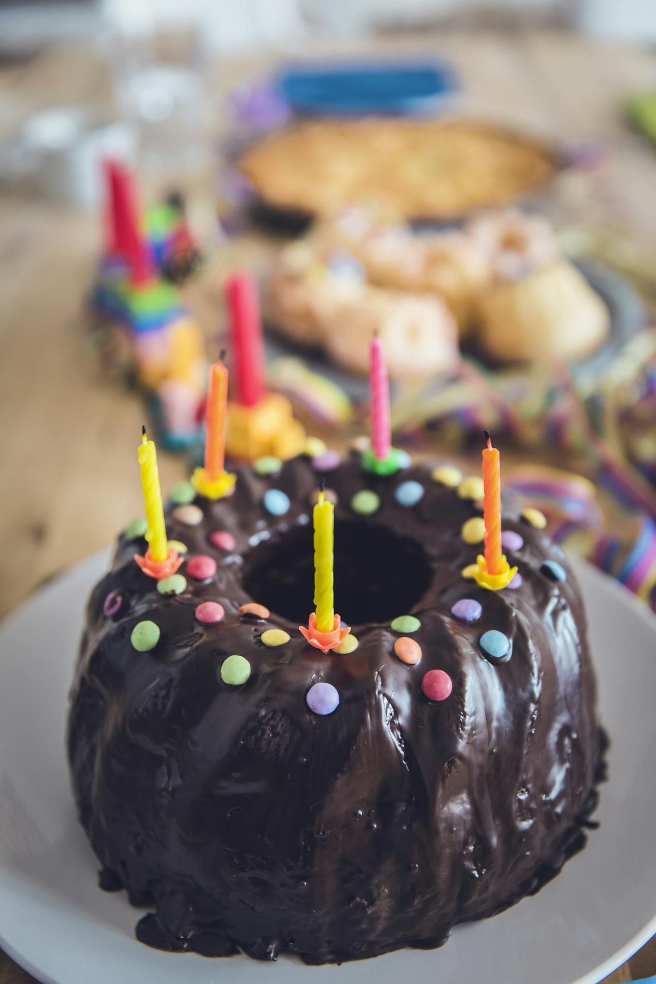 A delicious chocolate cake decorated with colorful candles and sprinkles, ready for a birthday celebration.