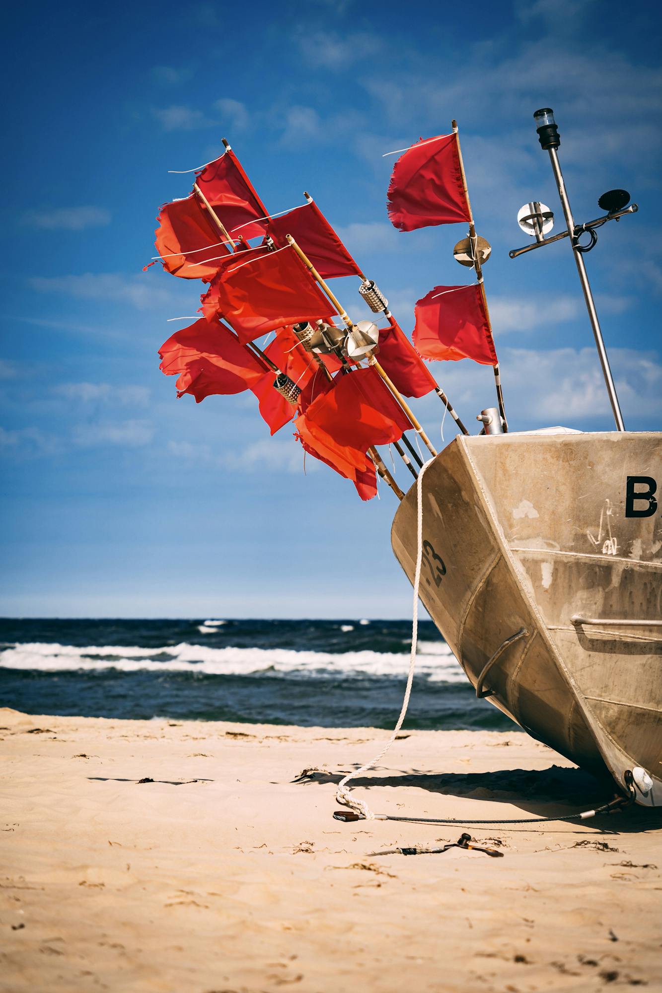Vibrant red flags on a boat at the sandy Baabe beach, Germany.
