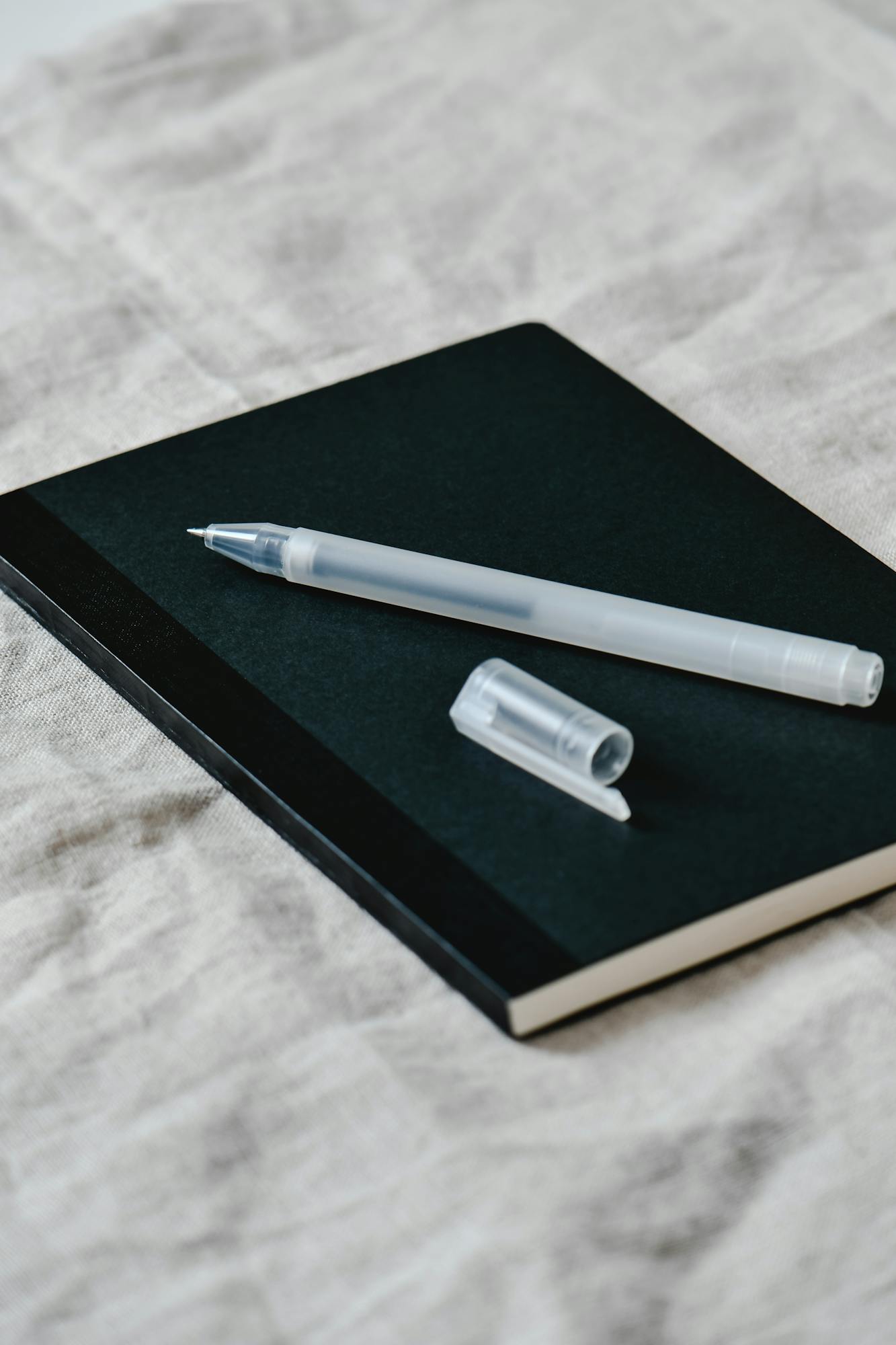 Close-up of a minimalist notebook with a pen on a textured fabric. Perfect for creative projects.