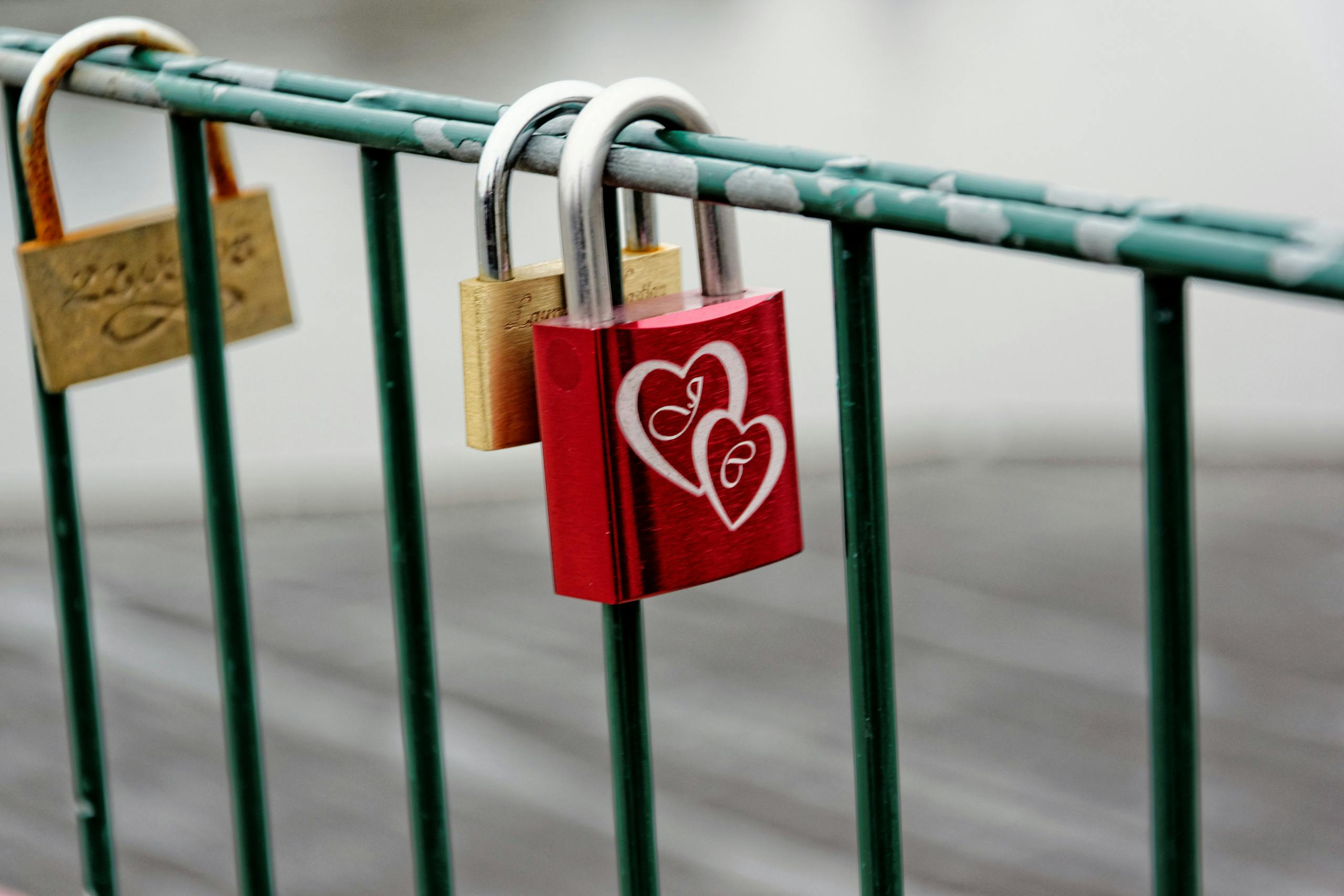 A vibrant red love padlock with heart engravings on a bridge railing symbolizing eternal love.