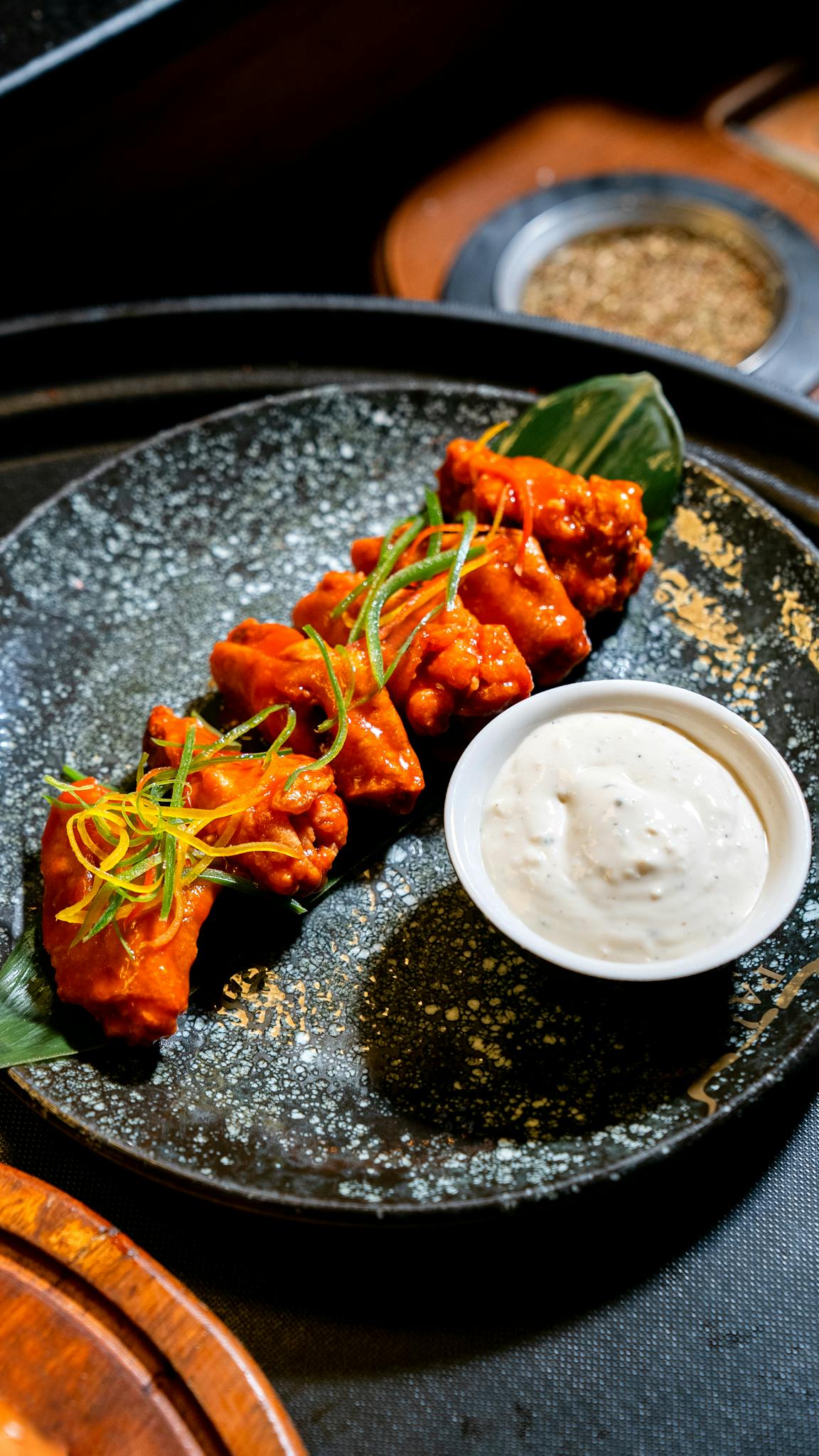 Crispy buffalo wings with creamy dip served on a stylish plate.